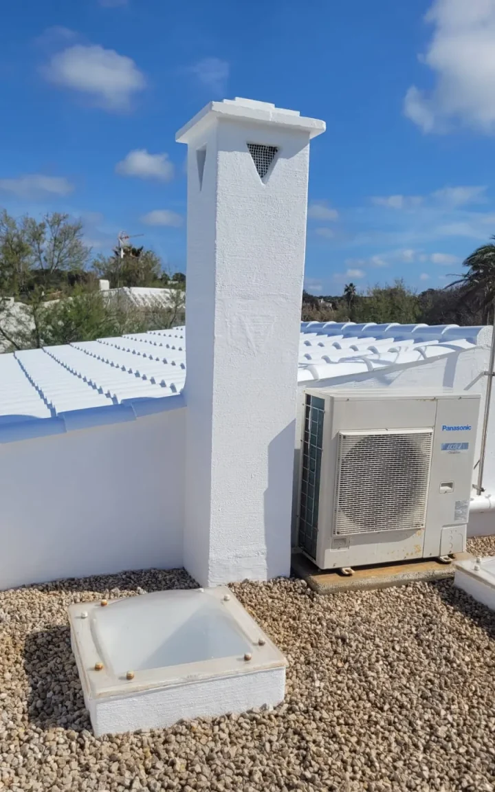 Chimenea menorquina y pretiles pintados en blanco sobre azotea de grava