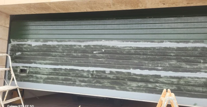Puerta de garaje durante la preparación: pintura vieja lijada y masilla en las zonas dañadas