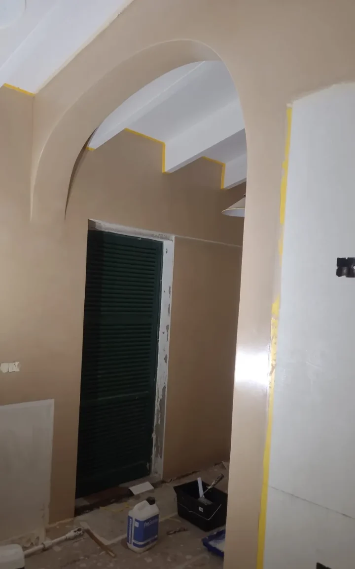 Arco de microcemento bajo techo de vigas blancas, con zona protegida durante la obra