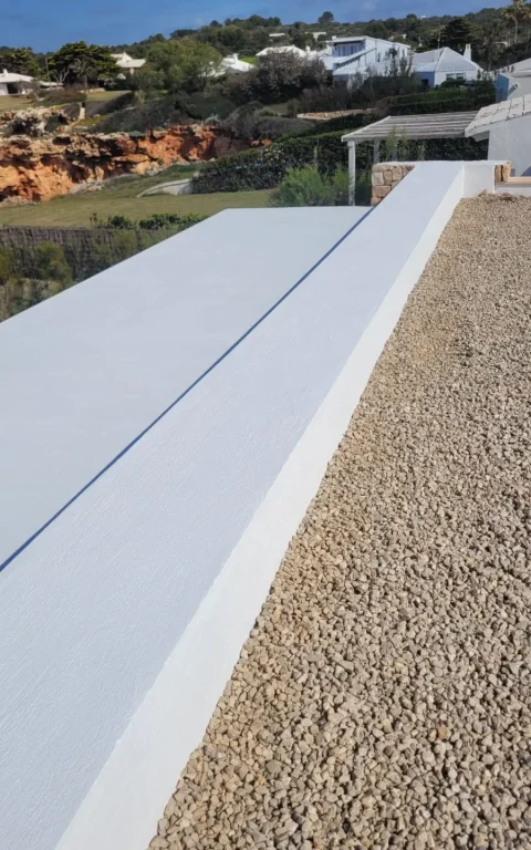 Remate de pretil pintado en blanco sobre azotea de grava